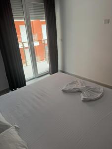 a white bed with an open window and a pillow at Banesa me Qera 15,36 Rana Hedhun in Lezhë