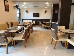 a dining room with tables and chairs and a tv at Hotel Sharanam in Shegaon