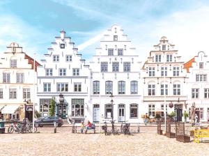 a group of white buildings with people sitting on a bench at BE BIO Hotel be active - Nähe historischer Hafen in Tönning