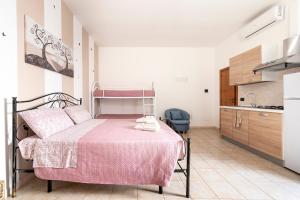 a bedroom with a pink bed and a kitchen at Lu Marchese in Minervino di Lecce