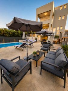 a patio with chairs and an umbrella and a pool at Our Villa - Villa Rena in Rethymno
