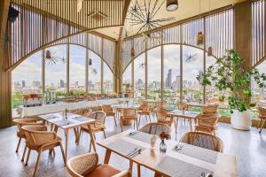 a restaurant with tables and chairs and large windows at Somerset Sukhumvit 71 Bangkok in Bangkok