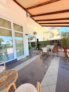 an outdoor patio with tables and chairs and windows at Premier Sea Apartment in Paleo Tsifliki