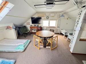 a room with a table and chairs and a bed at Guest House モモ in Obihiro