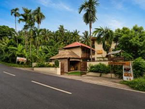 a building on the side of a road with palm trees at The Elysian Boutique Stays - Havelock in Havelock Island