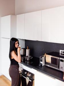 a woman standing in a kitchen drinking from a mug at Riverside Palace Apartments in Prague