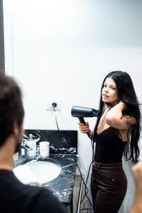 a woman standing in a bathroom blow drying her hair at Riverside Palace Apartments in Prague