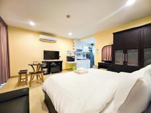 a bedroom with a large white bed and a kitchen at The Beach Bangsaen Condo 327/30 in Ban Bang Saen (1)