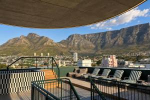 a balcony with chairs and mountains in the background at High-Floor Modern Apartment - Rooftop Pool & Table Mountain Views in Cape Town