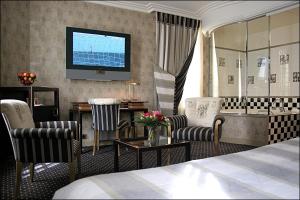 a hotel room with a bed and a television on the wall at Villa Lutèce Port Royal in Paris