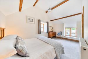 a white bedroom with a bed and a desk at The Barn in Corwen