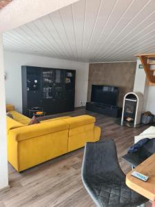 a living room with a yellow couch and a tv at Ferienwohnung Grahn 15154 in Leer