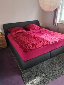 a bed in a bedroom with red sheets and pillows at Ferienwohnung Grahn 15154 in Leer +27 photos