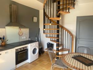 a kitchen with a spiral staircase next to a table at Loue appartement avec jardin in Alba-la-Romaine