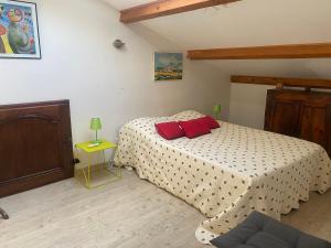a bedroom with a bed with two red pillows on it at Loue appartement avec jardin in Alba-la-Romaine