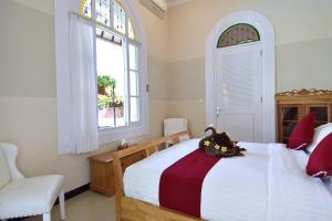 a bedroom with a bed and a chair and a window at Villa Mimosa in Lovina