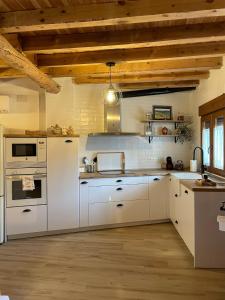 a kitchen with white appliances and wooden ceilings at El Rincón de la Plazuela in Romancos