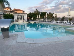 a large swimming pool with chairs and umbrellas at Anthos Casa Vacanze in SantʼOmero