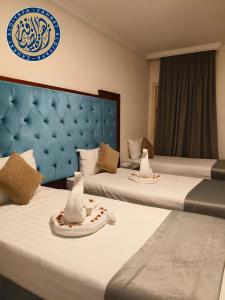 two beds in a hotel room with hats on them at Vivian AL Shasha in Mecca +16 photos