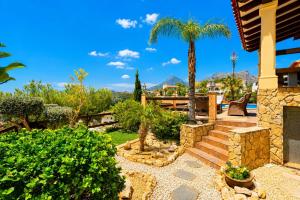 a garden with palm trees and a house at Cozy vacation home in Alfaz del Pi