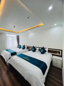 two beds in a hotel room with blue and white at Bảo Nhi Paradise Hotel in Làng Môn