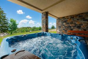 a hot tub in a backyard with a stone wall at ROGOChalet in Rogojel