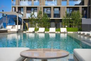 a swimming pool with lounge chairs and a building at Infinutum Sea Studio in Palanga