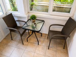 a glass table with two chairs and a potted plant at Apartment Be Happy 3, Premium Apartment in Ruse City Centre in Ruse