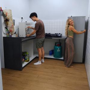 a man and a woman standing in a kitchen at No Plans No Complaints Backpackers Hostel in Ayer Itam +20 photos