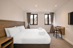 ein Hotelzimmer mit einem großen Bett und einem Schreibtisch in der Unterkunft The Manor Park Hotel in London + 66 Fotos