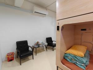 a room with a bed and a table and chairs at Sleepy Bear Capsule Hostel in Johor Bahru