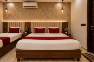 two beds in a hotel room with red pillows at Hotel The RG Grand Inn Near Chandigarh Railway Station in Chandīgarh