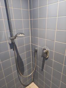 a shower with a hose in a blue tiled bathroom at DJH Jugendherberge Xanten in Xanten