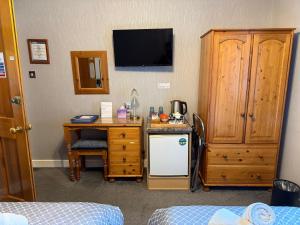 a room with a desk and a computer and a tv at Dionard Guest House in Inverness