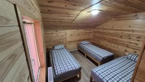 a room with two beds in a wooden cabin at Cabana Relax Time in Vălişoara