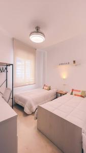 a white room with two beds and a window at Casa Yaye Ecija in Écija +33 photos