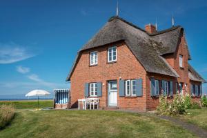 a large brick house with a thatched roof at Reethuus am Fething in Langeneß