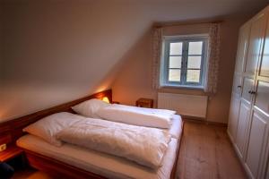a bedroom with two beds with white sheets and a window at Reethuus am Fething in Langeneß