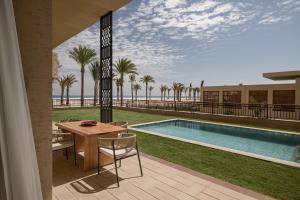 a patio with a table and chairs next to a swimming pool at Sakhra Hotel & Spa, Almaza Bay in Marsa Matruh