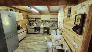 a kitchen with a table with chairs and a refrigerator at Cabana Relax Time in Vălişoara