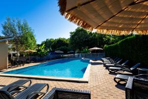 a swimming pool with chairs and an umbrella at Chalet Mauzac- Piscine- Domaine Paisible in Rivières