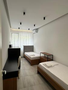 a bedroom with two beds and a desk and a window at EME APARTMENTS - Kompleksi Lura 2 Gjiri i Lalzit in Draç