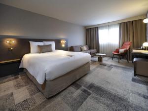 a hotel room with a large bed and a desk at Mercure Bordeaux Lac in Bordeaux