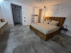 a bedroom with a large bed with a wooden headboard at Ssalamandra home's in Ocna-Mureşului