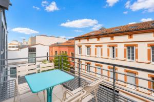 a blue table on a balcony with buildings at Appart Hôtel Clément Ader in Toulouse