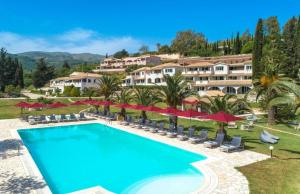 un resort con una grande piscina e ombrelloni rossi di Bella Mare Hotel a Kassiopi