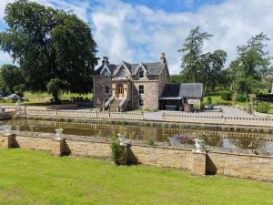 an old house with a pond in front of it at The Doune, Luxury Traditional Country House with hot tub in Inverness