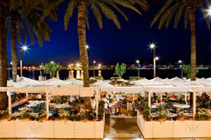 un ristorante con ombrelloni bianchi e palme di notte di CBbC Suites Port Vell a Ibiza Città