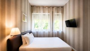 a bedroom with a bed with a television and a window at Hotel Salus in Pescara