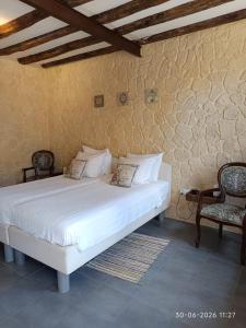 a bedroom with a white bed with two chairs at Gîte Chevannes - Holiday home - Pool - Parking - Mobility friendly - Pets welcome in Fours